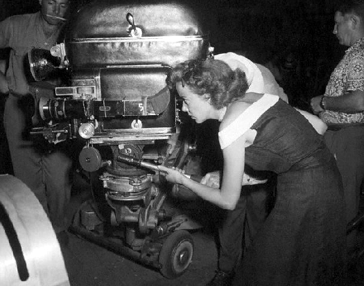 Hollywood, Los Angeles, California, USA --- Hollywood, CA:  Ida Lupino directs one of the scenes from her latest picture, "Mother of a Champion."  She is shown peering through the movie camera.  Undated photograph. --- Image by Â© Bettmann/CORBIS